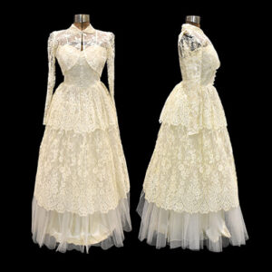 Floor-length wedding gown made of cream-coloured lace and tulle. It has a sweetheart neckline, spaghetti straps and and matching lace bolero with long sleeves.