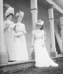 Three Women dressed in white on side porch.
